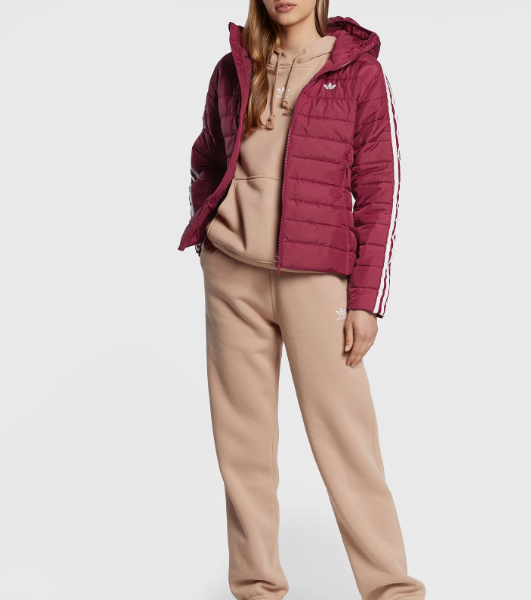 A woman wearing adidas hooded puffer jacket with a front zip closure. The jacket has a quilted design and a logo on the chest.