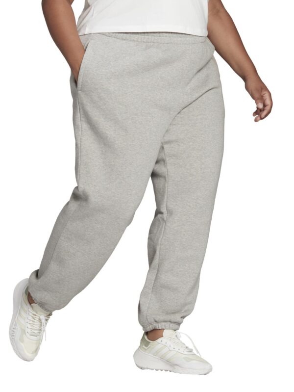 Adidas women's plus-size grey jogger pants with an elastic waistband, featuring side pockets and paired with white Adidas sneakers