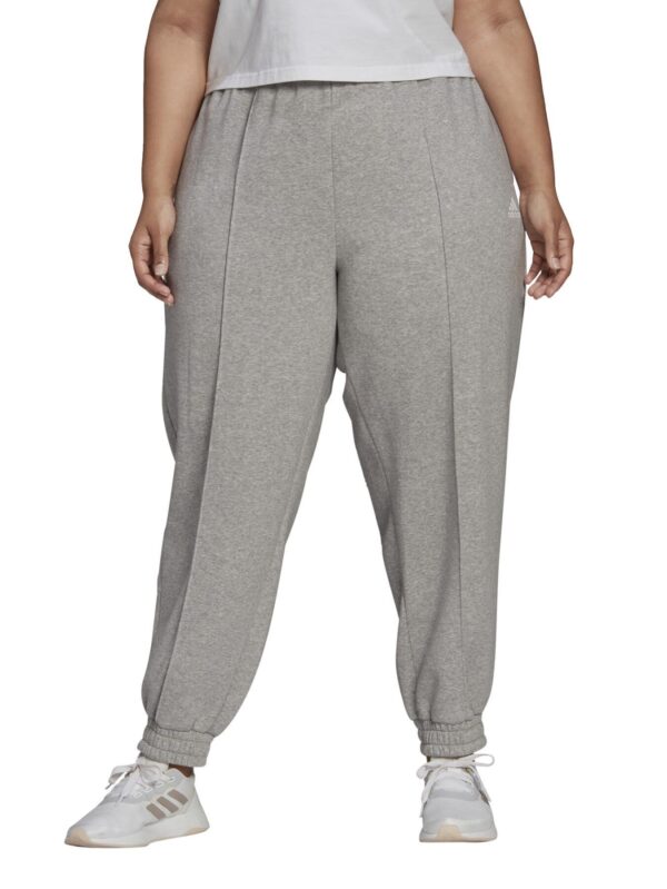 Adidas women's plus-size grey jogger pants with an elastic waistband, side pockets, and relaxed fit, styled with white Adidas sneakers