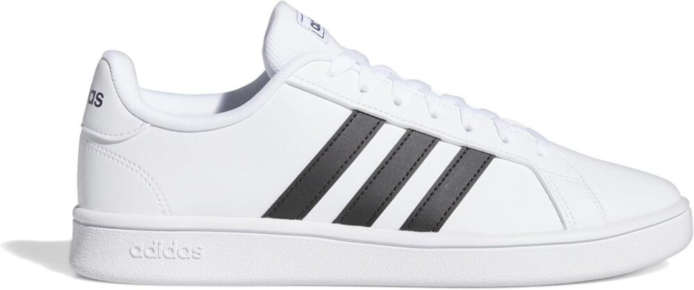 A pair of Adidas men's white sneakers with black stripes, shown on feet with blue joggers, ideal for casual or sporty wear.