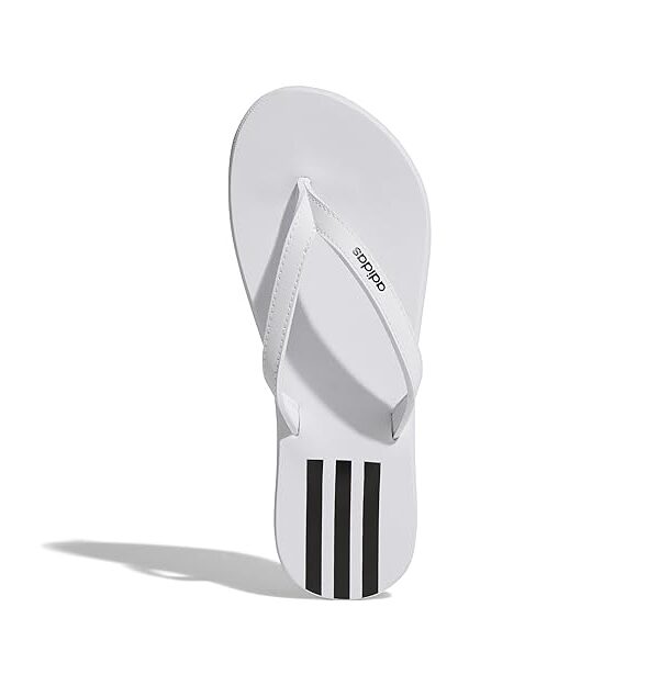 A pair of white Adidas Adilette Comfort Slides with black three stripes on the footbed.