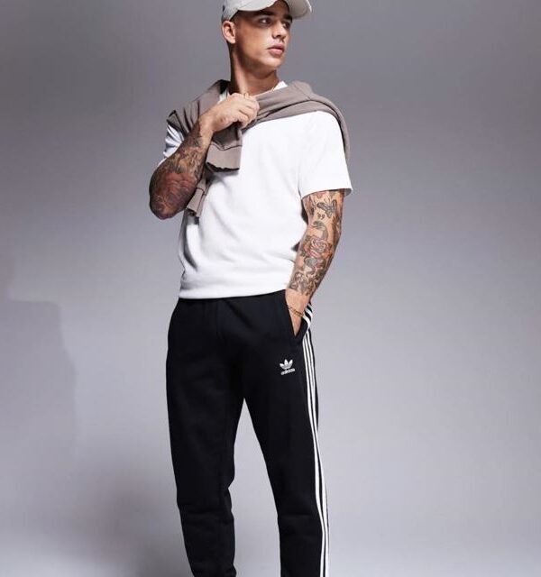 Adidas black track pants with white 3-stripes, slim fit, and ankle cuffs.