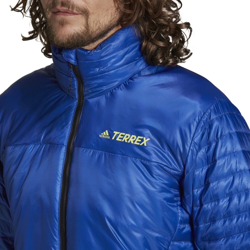 A man wearing an Adidas Terrex blue insulated jacket with a quilted design, full zip closure, and zippered pockets, ideal for outdoor adventures