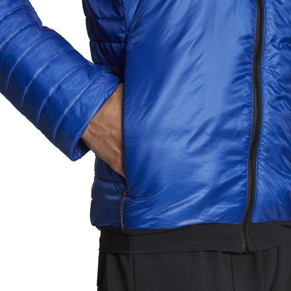 A man wearing an Adidas Terrex blue insulated jacket with a quilted design, full zip closure, and zippered pockets, ideal for outdoor adventures