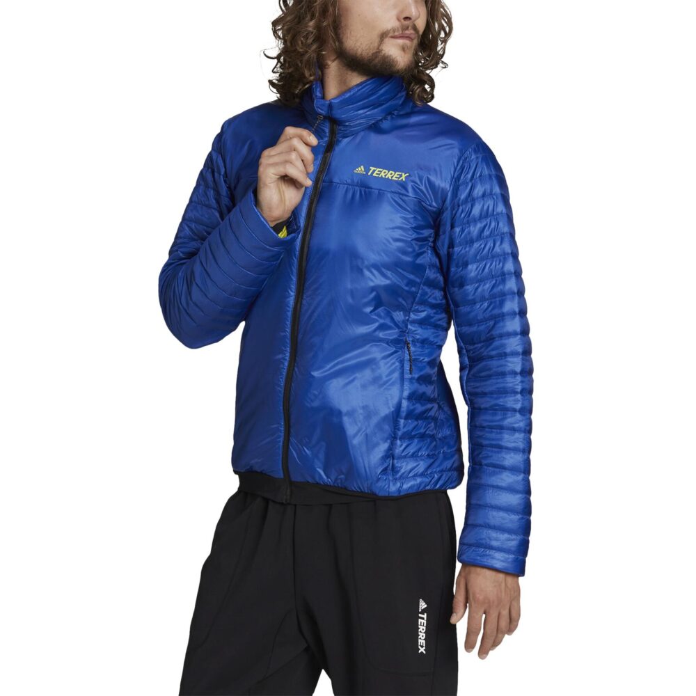 A man wearing an Adidas Terrex blue insulated jacket with a quilted design, full zip closure, and zippered pockets, ideal for outdoor adventures