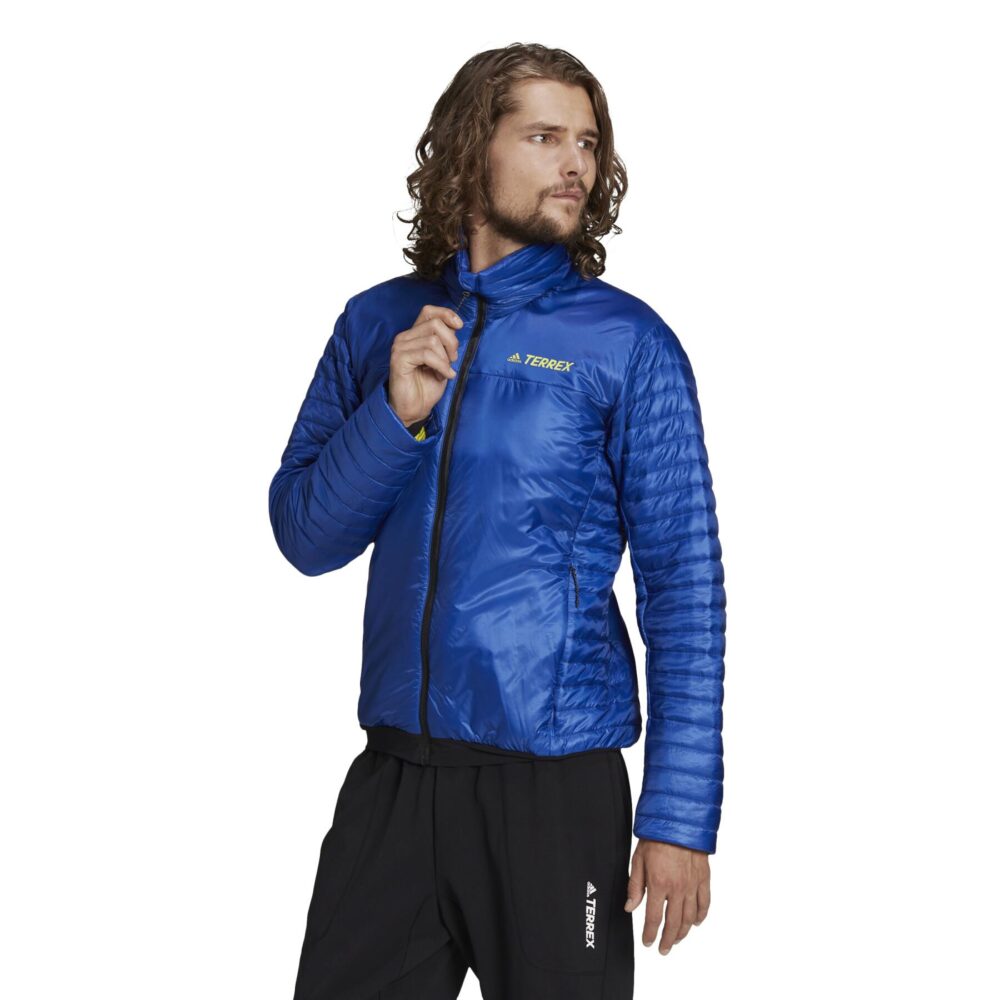 A man wearing an Adidas Terrex blue insulated jacket with a quilted design, full zip closure, and zippered pockets, ideal for outdoor adventures