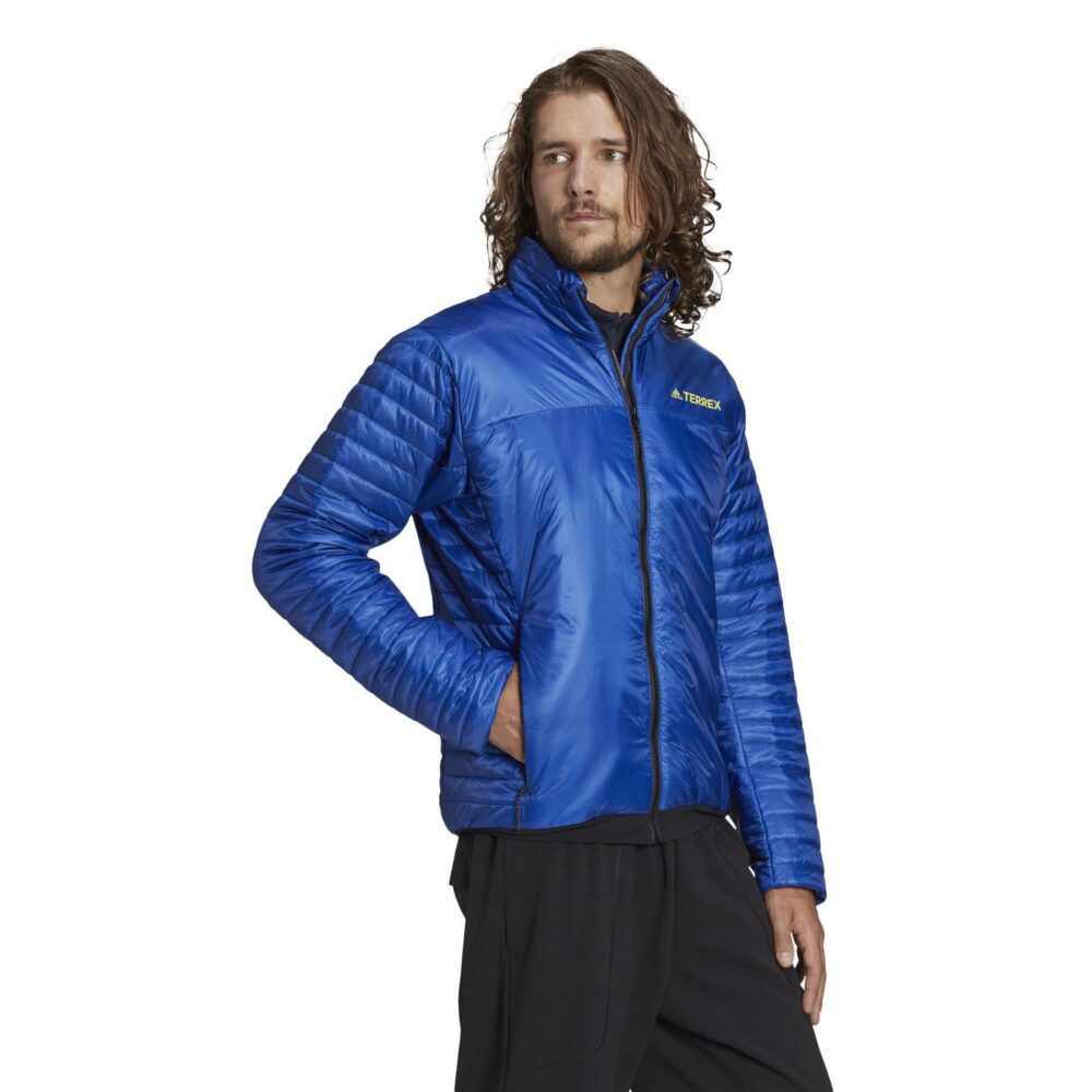 A man wearing an Adidas Terrex blue insulated jacket with a quilted design, full zip closure, and zippered pockets, ideal for outdoor adventures