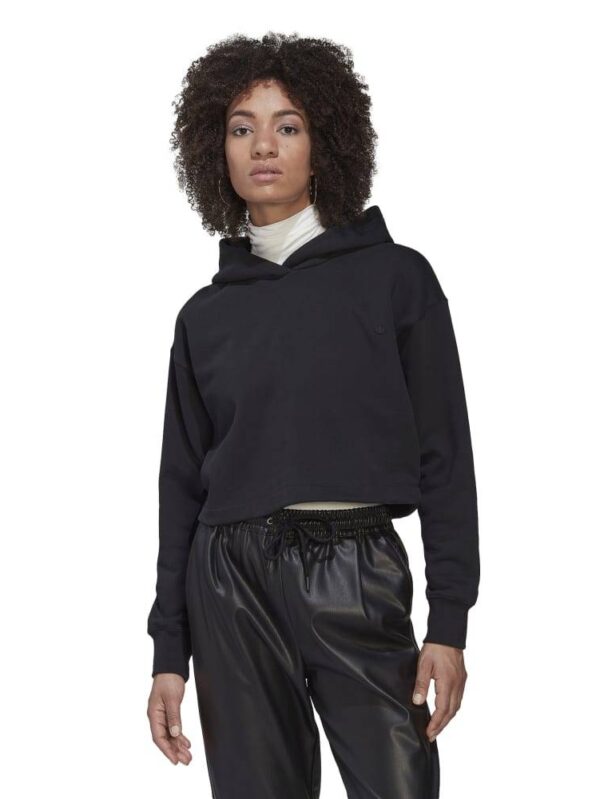 A woman wearing a black cropped hoodie paired with high-waisted black pants, showcasing a sleek and modern casual look