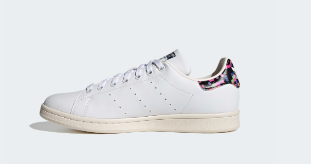 A pair of white Adidas Stan Smith Shoes with a colorful heel tab.