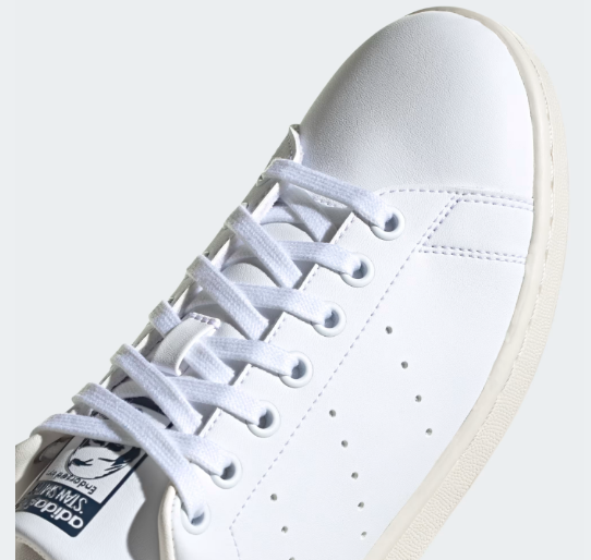 A pair of white Adidas Stan Smith Shoes with a colorful heel tab.